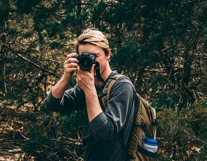 Person photographing in a forested area.
