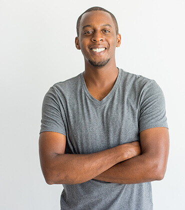 Smiling man in gray shirt, arms crossed.