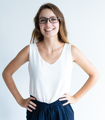 Smiling woman with glasses and hands on hips.