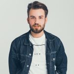 Man wearing denim jacket and white shirt.
