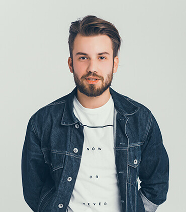 Man wearing denim jacket and white shirt.