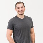 Smiling man in gray t-shirt, standing.