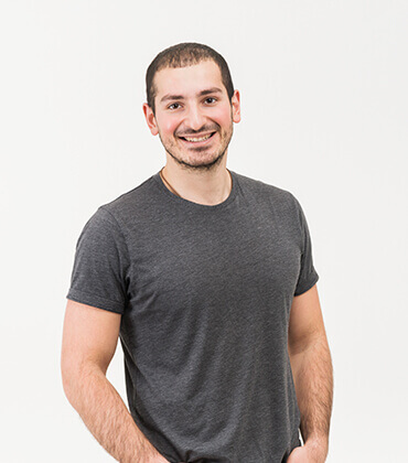 Smiling man in gray t-shirt, standing.