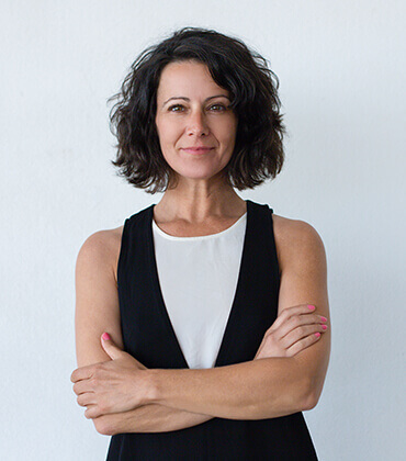 Woman with short hair, arms crossed, smiling.