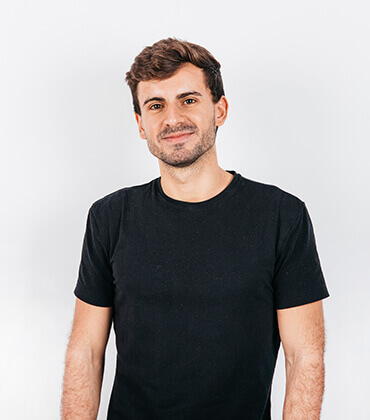 Man in black shirt smiling confidently.