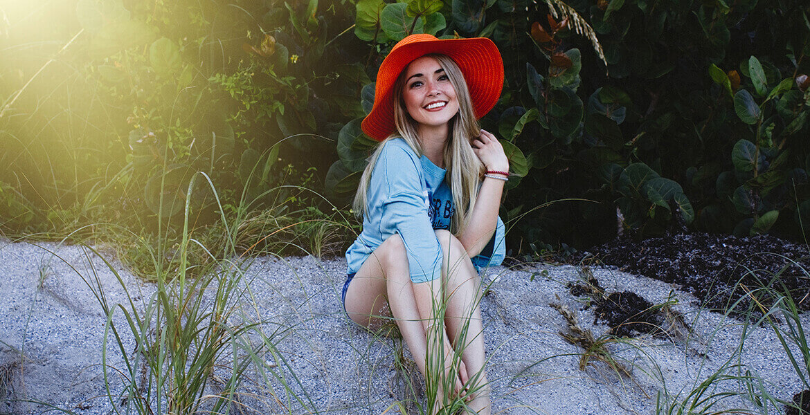 Smiling woman in red hat on beach.