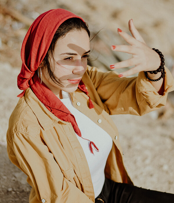Woman with red headscarf shielding eyes.